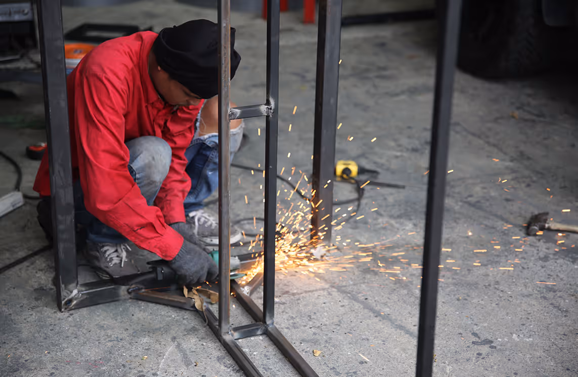 Metallbauer schleift eine Stahlkonstruktion in der Werkstatt